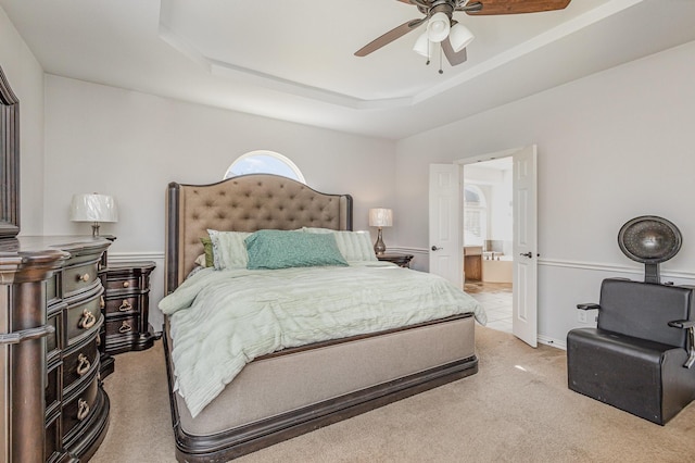 carpeted bedroom featuring ceiling fan, connected bathroom, and a raised ceiling