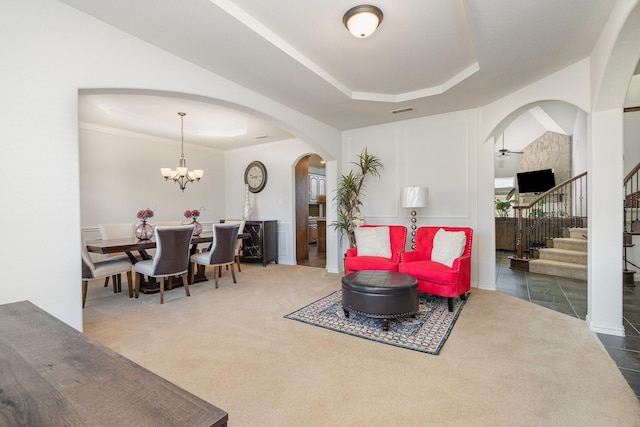 carpeted living room with a tray ceiling and a notable chandelier