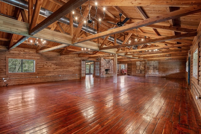 interior space with ceiling fan, wooden walls, vaulted ceiling with beams, and wood ceiling