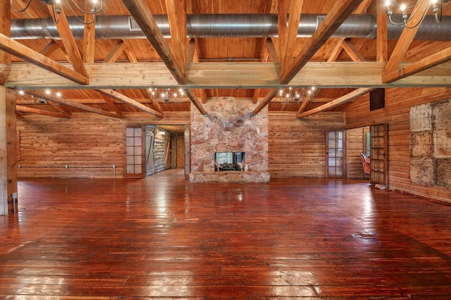 unfurnished living room with a fireplace, wood walls, beamed ceiling, wood-type flooring, and wood ceiling