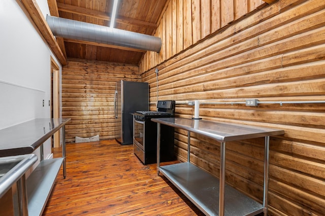 kitchen with dark hardwood / wood-style flooring, a towering ceiling, stainless steel range with gas stovetop, and wooden walls