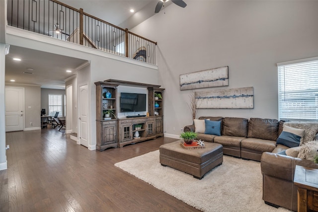 living room with ceiling fan, wood-type flooring, a towering ceiling, and a wealth of natural light