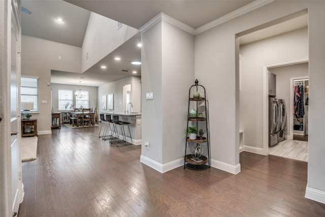 interior space with crown molding, wood-type flooring, sink, and washing machine and dryer