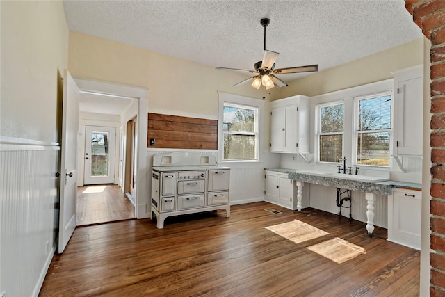 unfurnished office with a textured ceiling, dark hardwood / wood-style floors, and white cabinets