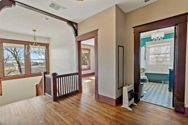 hall featuring heating unit, hardwood / wood-style flooring, and a chandelier