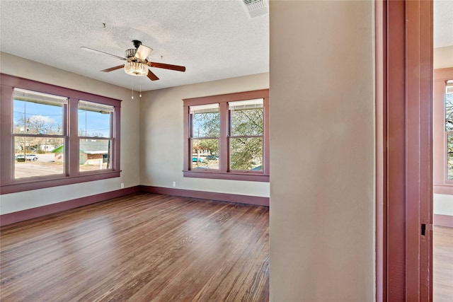 spare room with hardwood / wood-style flooring, a healthy amount of sunlight, a textured ceiling, and ceiling fan