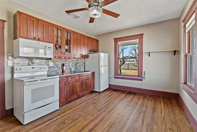 kitchen featuring white appliances, ceiling fan, hardwood / wood-style floors, backsplash, and a textured ceiling