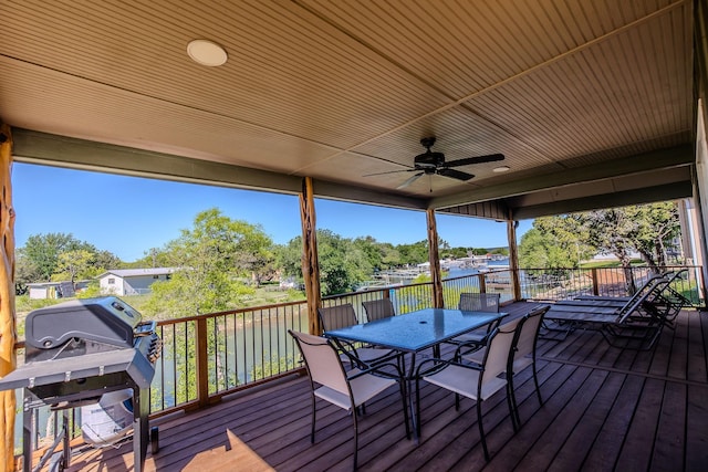 wooden deck with grilling area, ceiling fan, and a water view