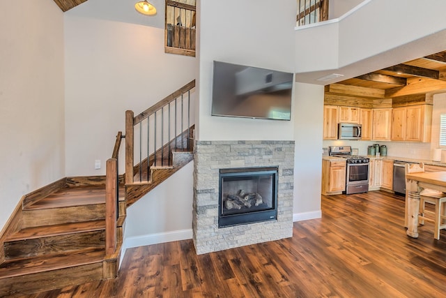 living room featuring dark wood-type flooring, beam ceiling, a stone fireplace, and wooden ceiling