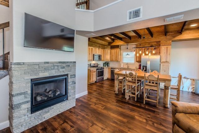 dining area with a fireplace, sink, dark wood-type flooring, wooden ceiling, and beam ceiling