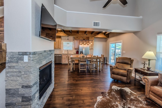 living room with ceiling fan, a stone fireplace, and dark hardwood / wood-style flooring