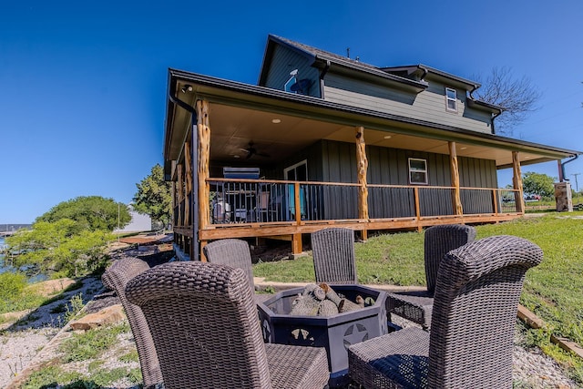 rear view of property with ceiling fan and an outdoor fire pit