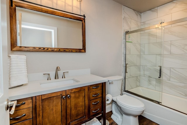 full bathroom featuring vanity, hardwood / wood-style floors, toilet, and combined bath / shower with glass door