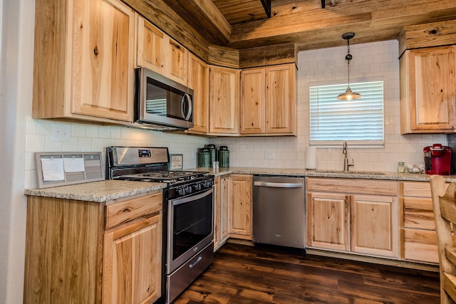 kitchen featuring sink, dark hardwood / wood-style flooring, pendant lighting, stainless steel appliances, and light stone countertops