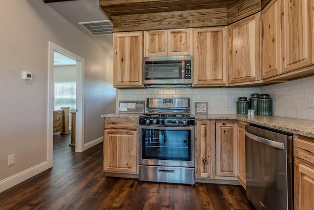 kitchen featuring light stone counters, appliances with stainless steel finishes, dark wood-type flooring, and light brown cabinets