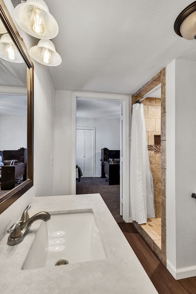 bathroom with walk in shower, vanity, hardwood / wood-style floors, and a textured ceiling