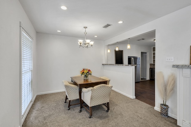 carpeted dining room featuring a notable chandelier