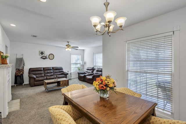 dining space with ceiling fan with notable chandelier and light carpet