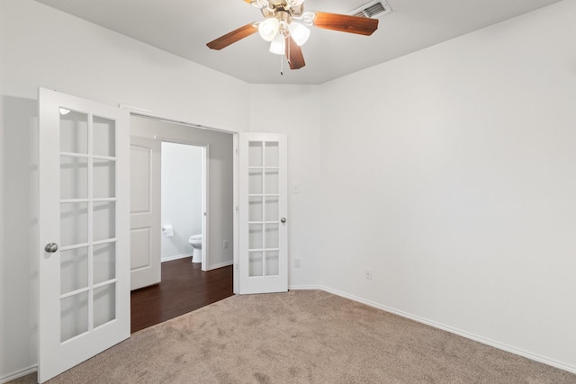 spare room with french doors, ceiling fan, and dark colored carpet