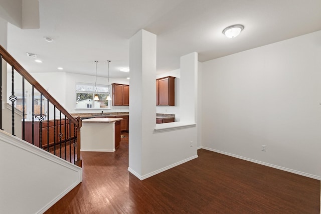 interior space with pendant lighting, dark hardwood / wood-style floors, a kitchen breakfast bar, and kitchen peninsula