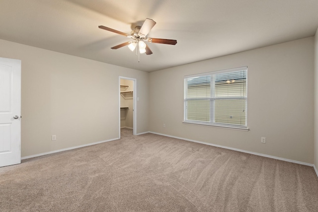 unfurnished bedroom featuring a walk in closet, light colored carpet, ceiling fan, and a closet