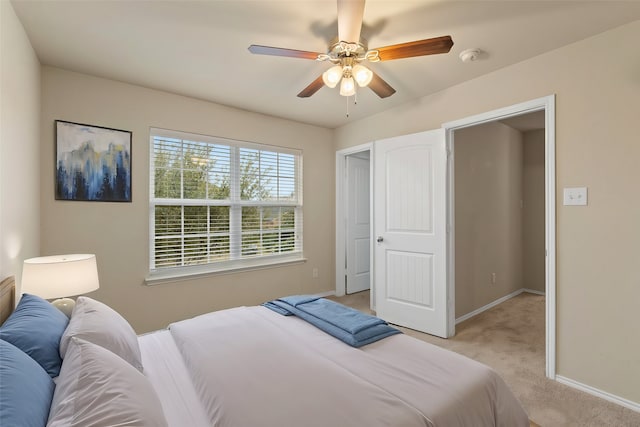 bedroom featuring light carpet, baseboards, and a ceiling fan