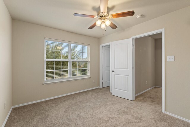 unfurnished bedroom with ceiling fan, baseboards, and light colored carpet