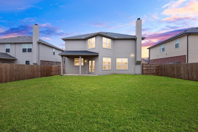 back of house featuring a patio area, a fenced backyard, a yard, and a chimney