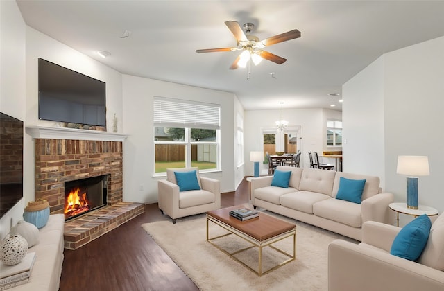 living area with a brick fireplace, a ceiling fan, and wood finished floors