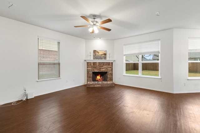 unfurnished living room with ceiling fan, a brick fireplace, and dark hardwood / wood-style flooring