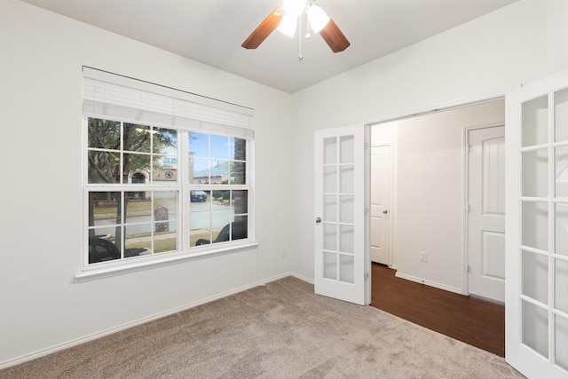 carpeted spare room featuring ceiling fan and french doors