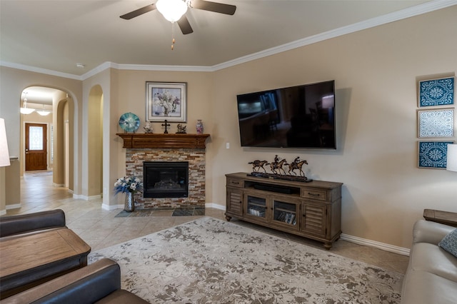 tiled living room featuring crown molding, ceiling fan, and a fireplace