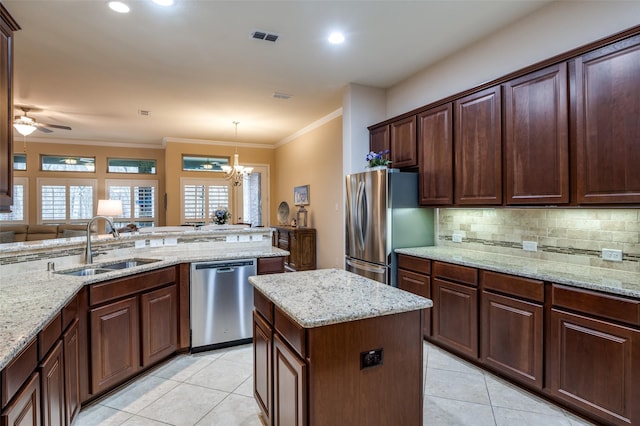 kitchen featuring stainless steel appliances, light stone countertops, hanging light fixtures, and sink