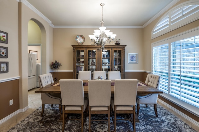 dining room featuring tile patterned flooring, ornamental molding, and an inviting chandelier