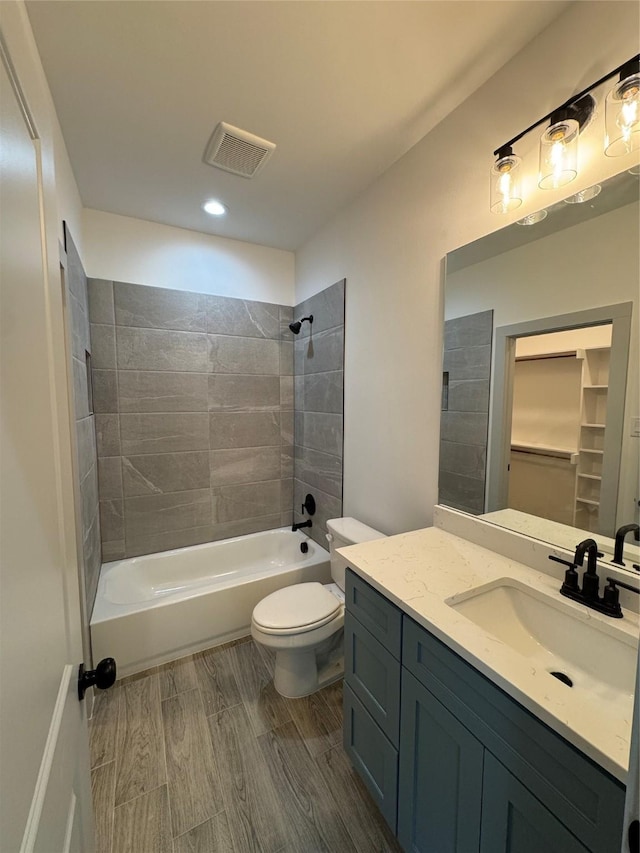 full bathroom featuring tiled shower / bath, vanity, and toilet