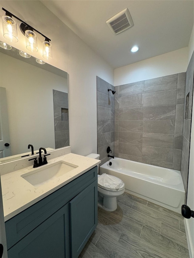 full bathroom with tiled shower / bath, vanity, and toilet