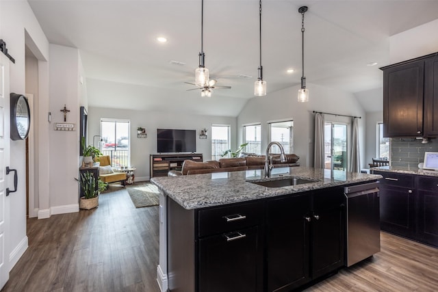 kitchen featuring a kitchen island with sink, sink, vaulted ceiling, and stainless steel dishwasher