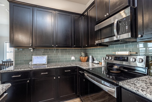 kitchen with dark brown cabinetry, appliances with stainless steel finishes, and light stone countertops