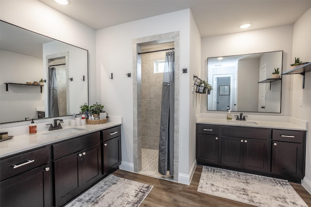 bathroom with wood-type flooring, vanity, and a tile shower