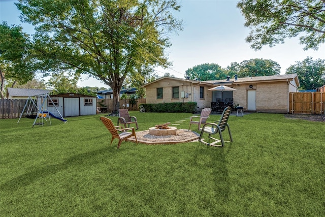 view of yard featuring an outdoor fire pit, a playground, and a shed