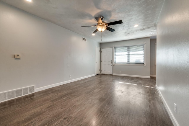 empty room featuring a textured ceiling, dark hardwood / wood-style floors, and ceiling fan