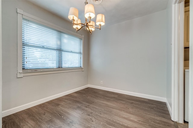 spare room featuring dark hardwood / wood-style flooring and a notable chandelier