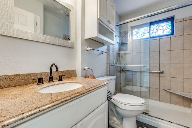 bathroom featuring a shower with door, vanity, and toilet