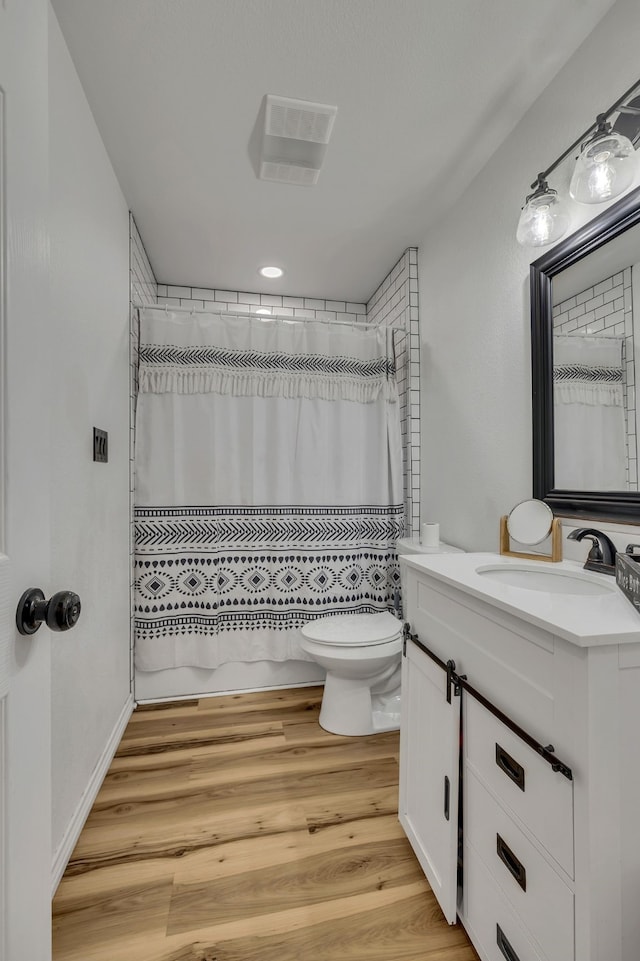 full bathroom featuring hardwood / wood-style flooring, vanity, shower / bath combo with shower curtain, and toilet