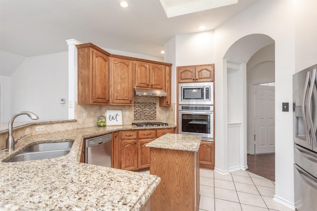 kitchen featuring a kitchen island, appliances with stainless steel finishes, sink, light tile patterned floors, and light stone countertops