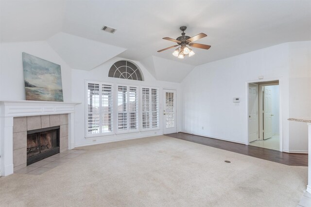 unfurnished living room featuring lofted ceiling, light colored carpet, a tile fireplace, and ceiling fan