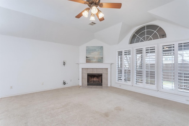 unfurnished living room with a tiled fireplace, vaulted ceiling, light colored carpet, and ceiling fan