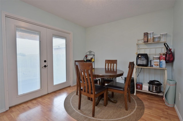 dining space featuring light hardwood / wood-style flooring, french doors, and a textured ceiling