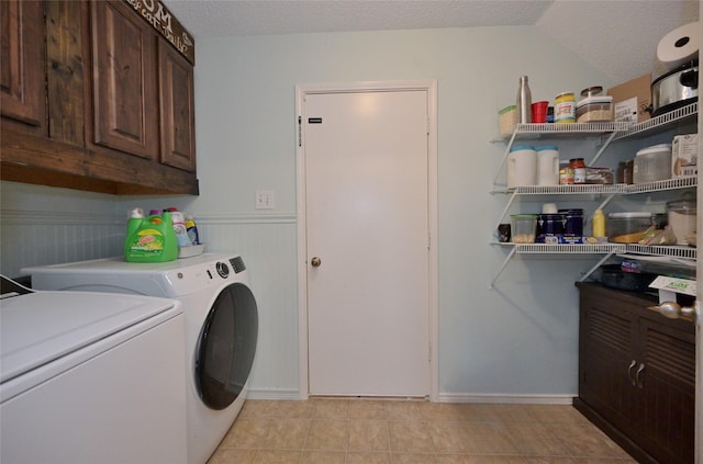 washroom with cabinets, separate washer and dryer, light tile patterned floors, and a textured ceiling