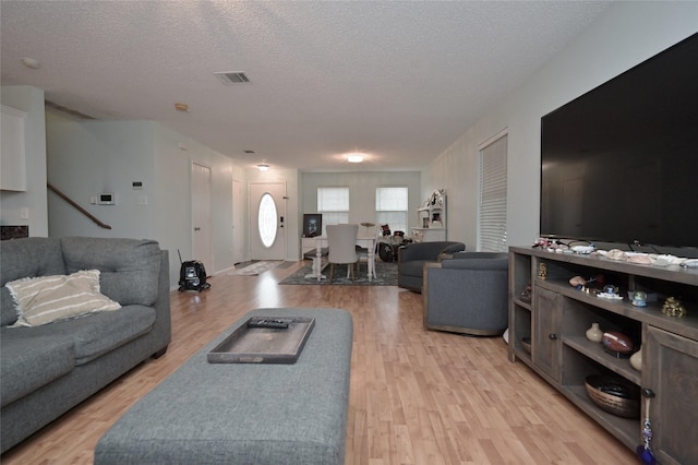 living room with a textured ceiling and light wood-type flooring